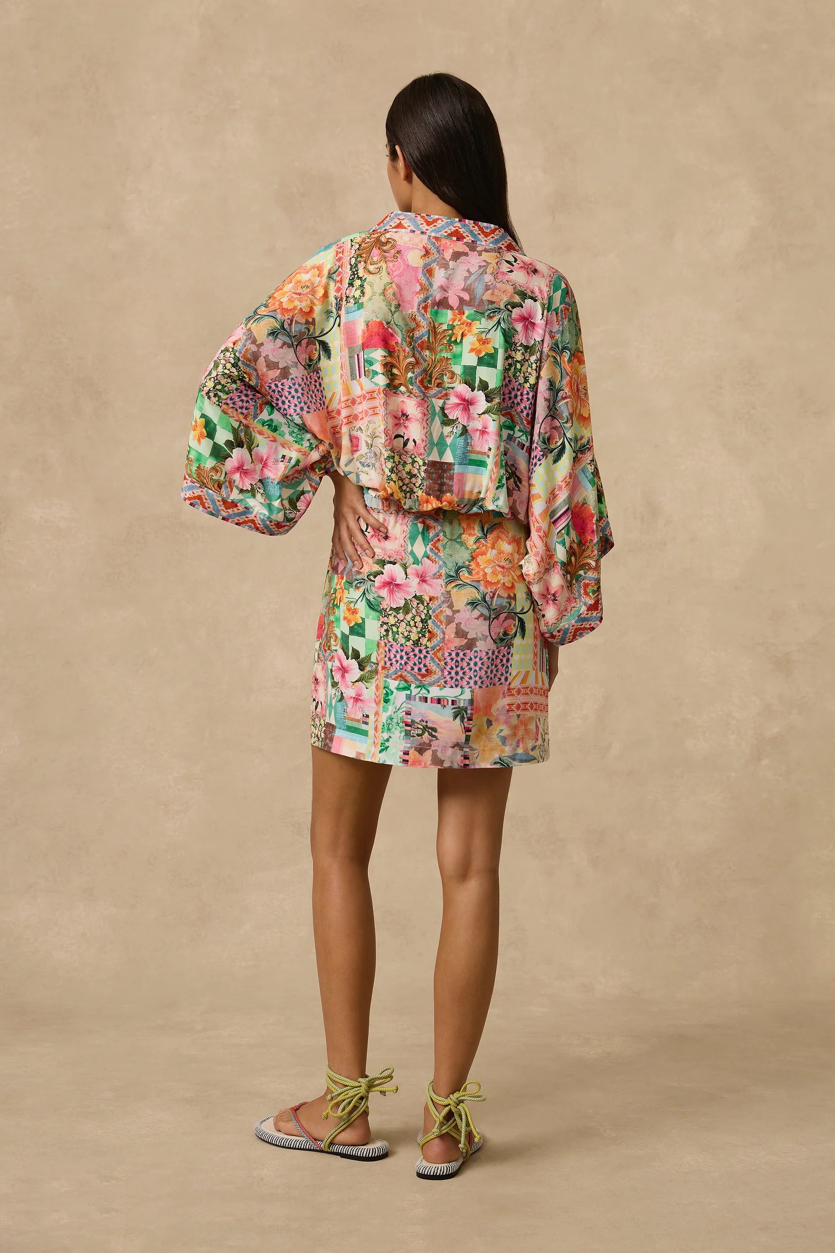 The Simi Kimono Mini Dress features a wrap front and wide kimono sleeve with border print band edge. Self Drawcord waist tie with coloured bead detail and straight skirt. Straight skirt.
