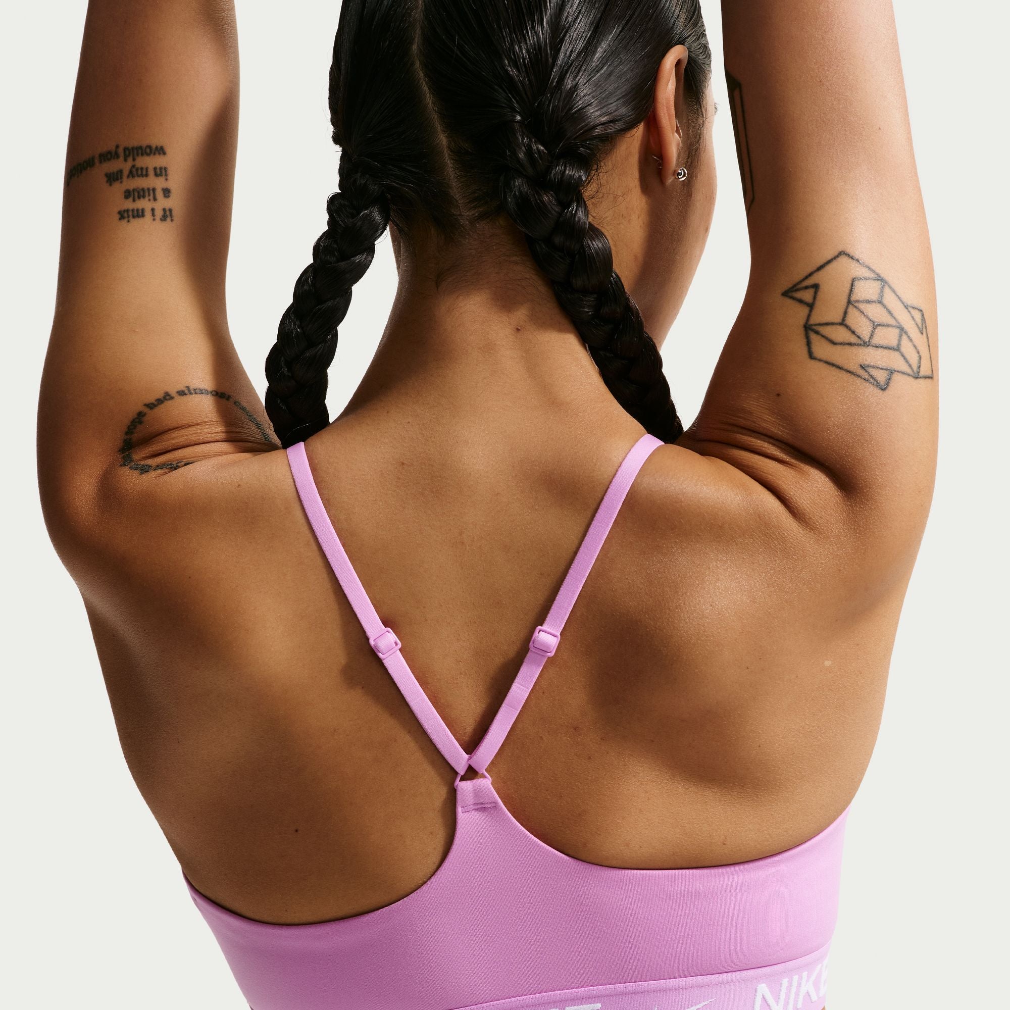 Person wearing a pink Nike sports bra with a white background
