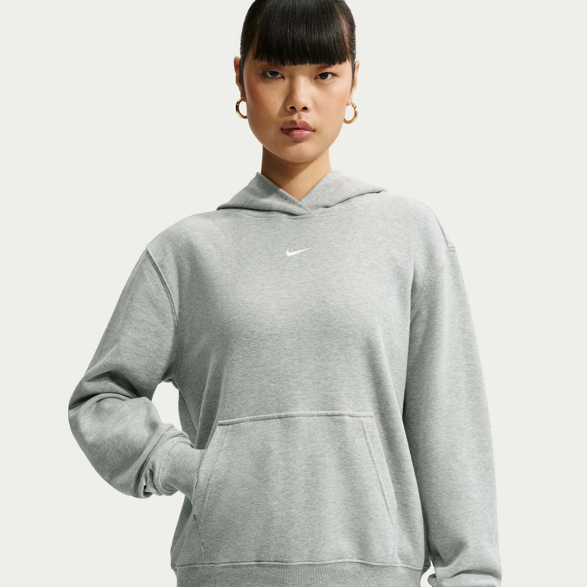 Person wearing a grey Nike hoodie on a white background