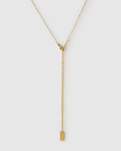 A delicate gold Y-necklace with a short chain, lobster clasp, extender chain, and a small rectangular engraved tag 