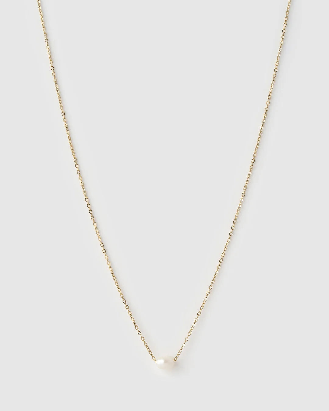 A delicate gold chain necklace with a small, round white pearl pendant, displayed against a solid light gray background.