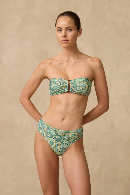 The Lulu Mid Rise Ruched Bikini Pant features a wide ruched front waist panel with fuller coverage through the front length and a higher cut leg that visually elongates the thigh.