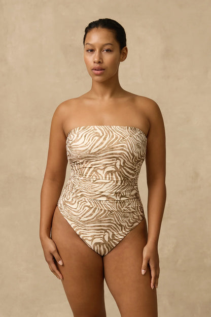 The Nova Ruched Bandeau One Piece features ruching throughout the front body to visually slim and shape, a shelf bra, gripper around the neck and boning in the side seams. 