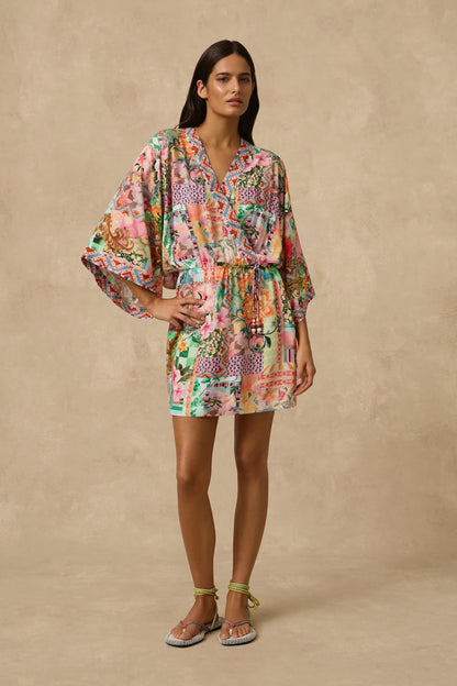 The Simi Kimono Mini Dress features a wrap front and wide kimono sleeve with border print band edge. Self Drawcord waist tie with coloured bead detail and straight skirt.  Straight skirt.
