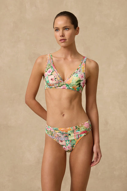 The Simi Mid Rise Ruched Bikini Pant features a wide ruched front waist panel with fuller coverage through the front length and a higher cut leg that visually elongates the thigh.