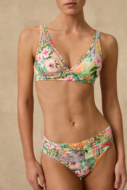 The Simi Mid Rise Ruched Bikini Pant features a wide ruched front waist panel with fuller coverage through the front length and a higher cut leg that visually elongates the thigh.