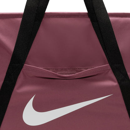Close-up of a Nike duffel bag in dusty rose with black shoulder straps and a large white Nike swoosh logo on the front.