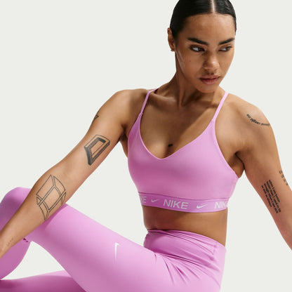Woman wearing a pink Nike sports bra and leggings on a light gray background