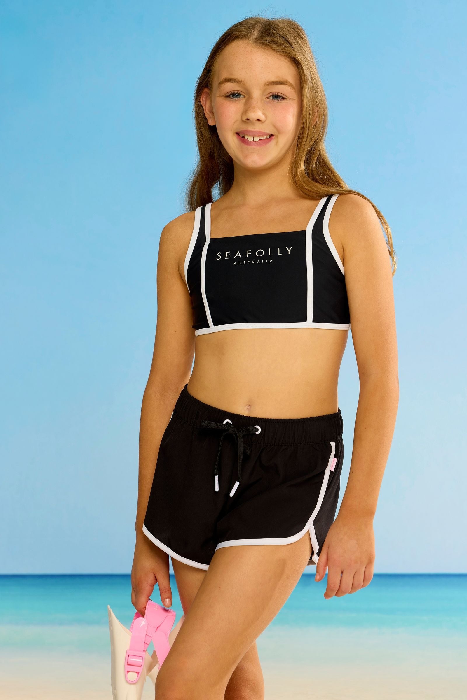 Seafolly Girls Essentials Boardshort in Black features an elasticated waistband, draw cord, scallop hemline, contrast piping.